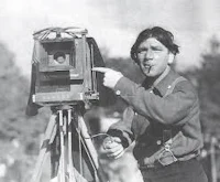 a man with a camera standing next to a tripod